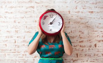 woman covering face using wall clock